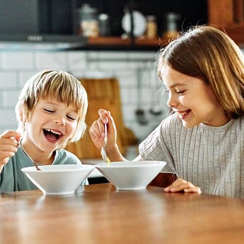 Two children eating a reduced sugar breakfast.